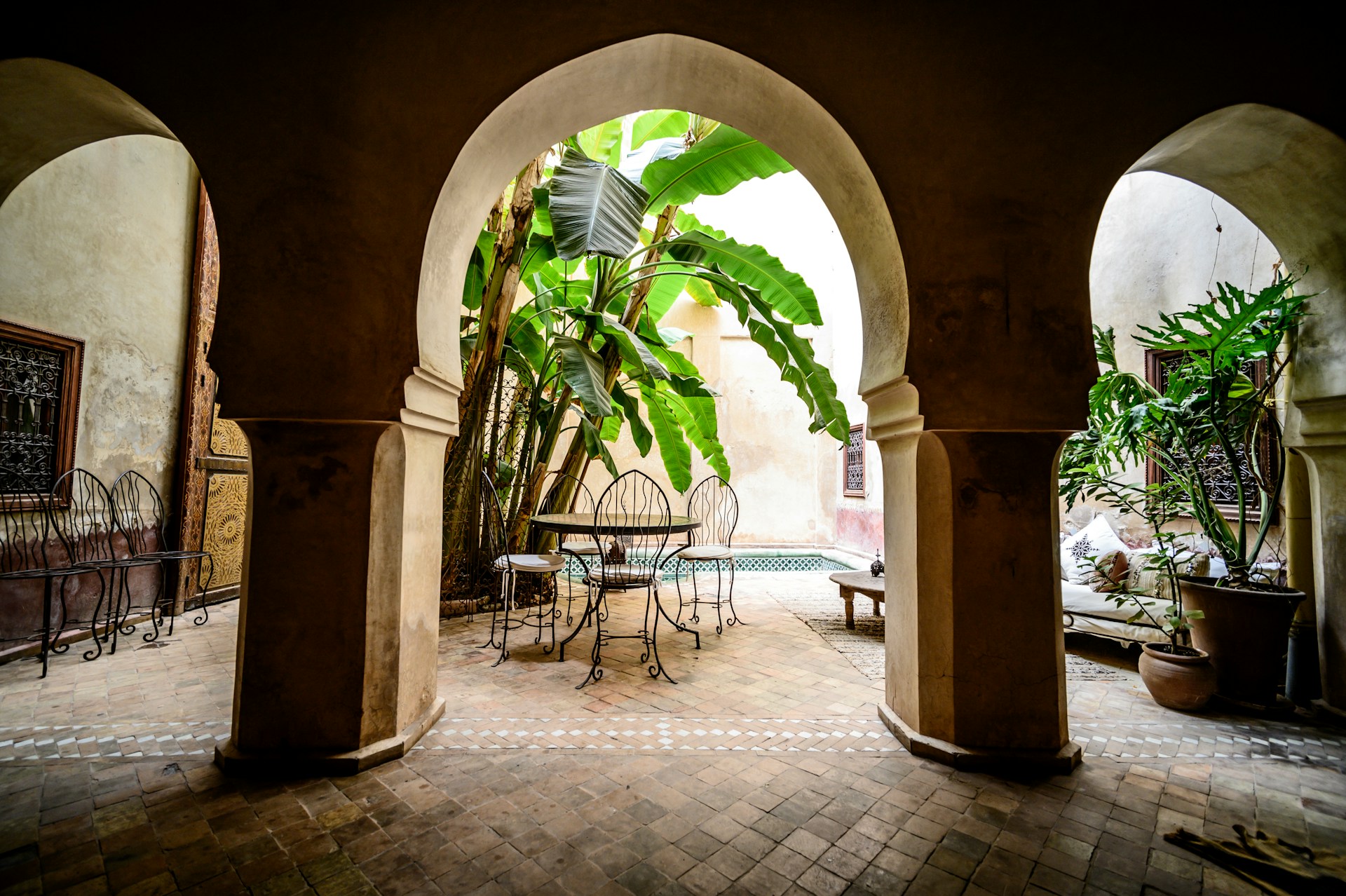 a courtyard with a table and chairs and a potted plant