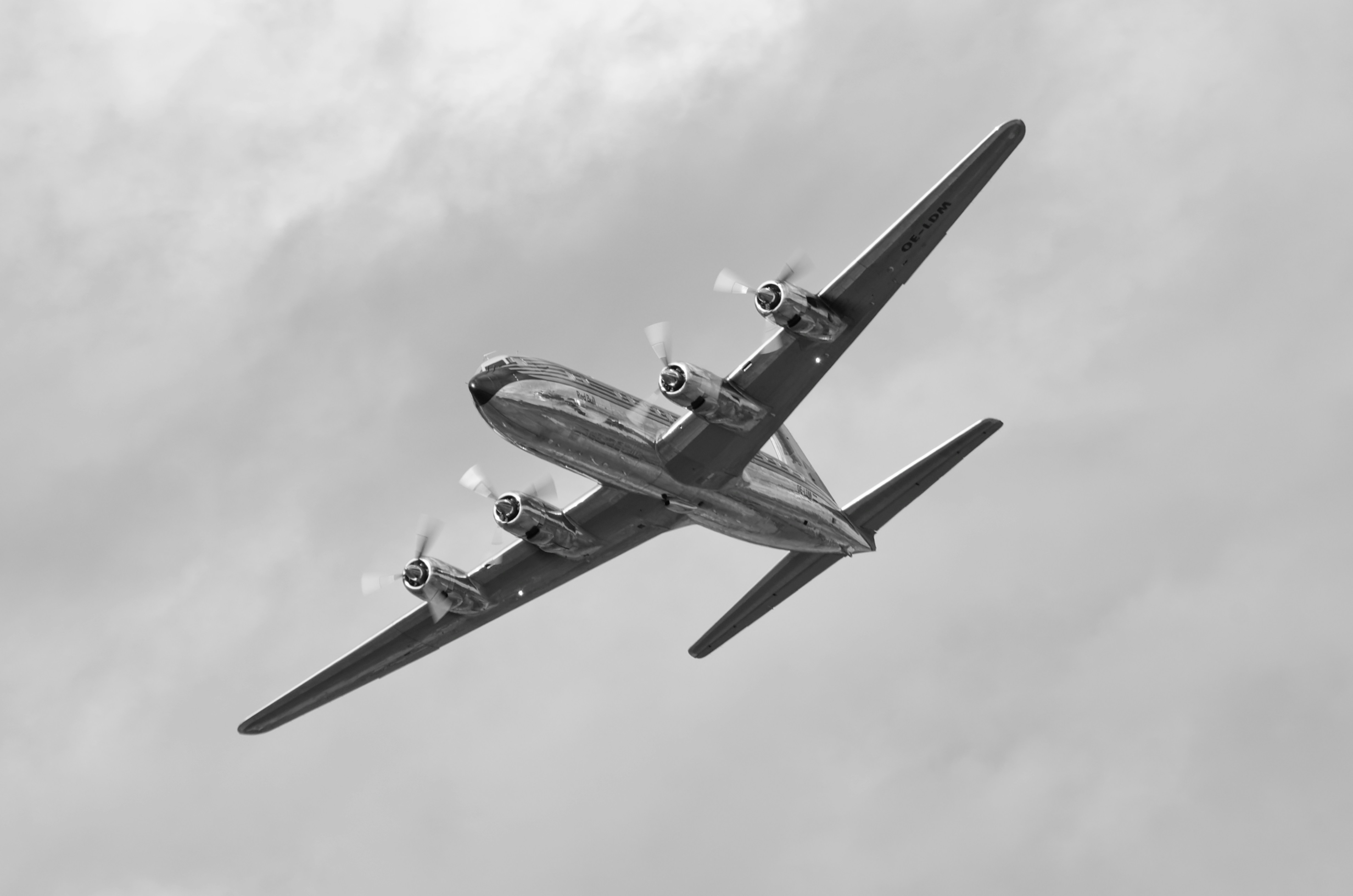a propeller plane flying through a cloudy sky, Flying Bulls Douglas DC-6B at Airpower 2022.