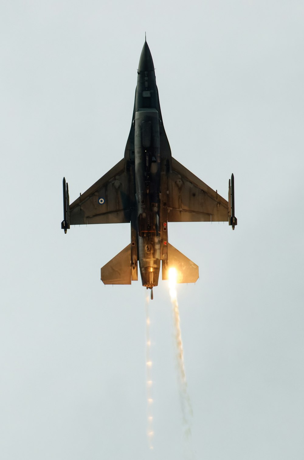 a fighter jet flying through the air with a trail of smoke coming out of it