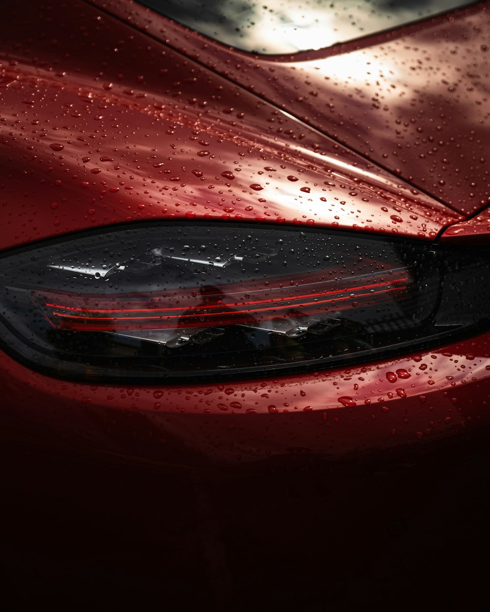 a close up of a red car with rain drops on it