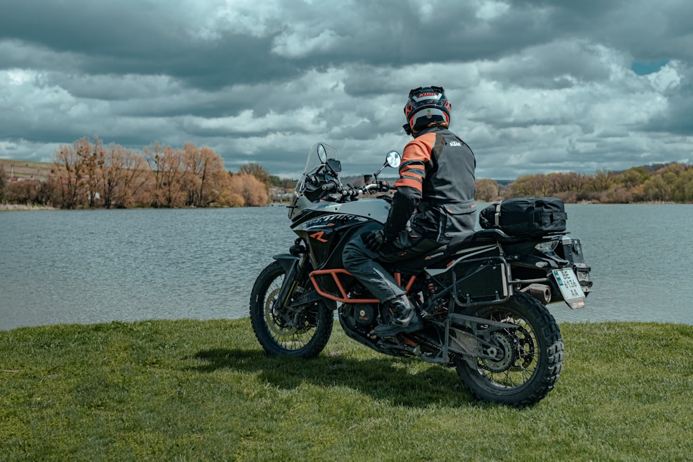 a man sitting on a motorcycle next to a lake