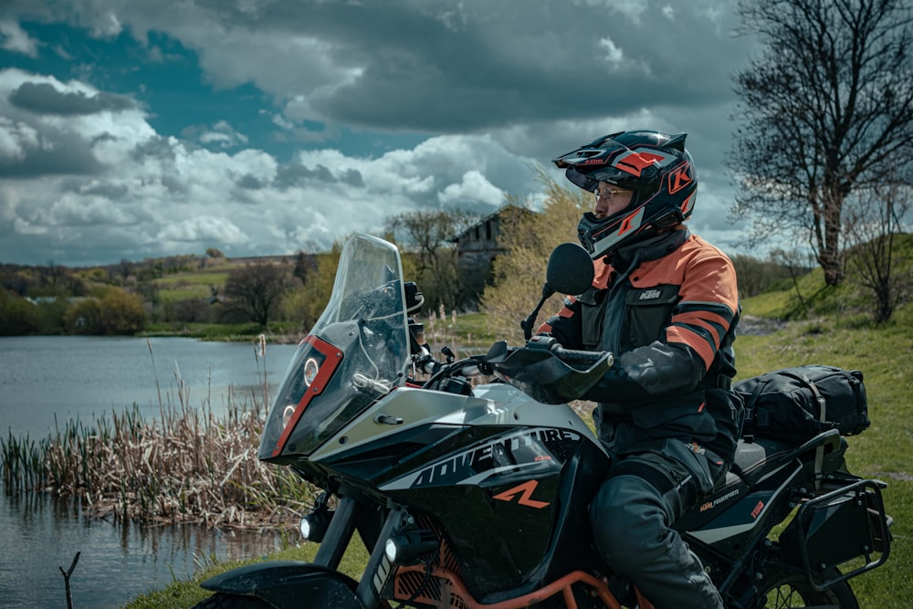 a man riding on the back of a motorcycle next to a lake