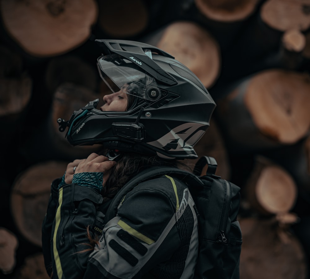 a person wearing a helmet standing in front of a pile of logs