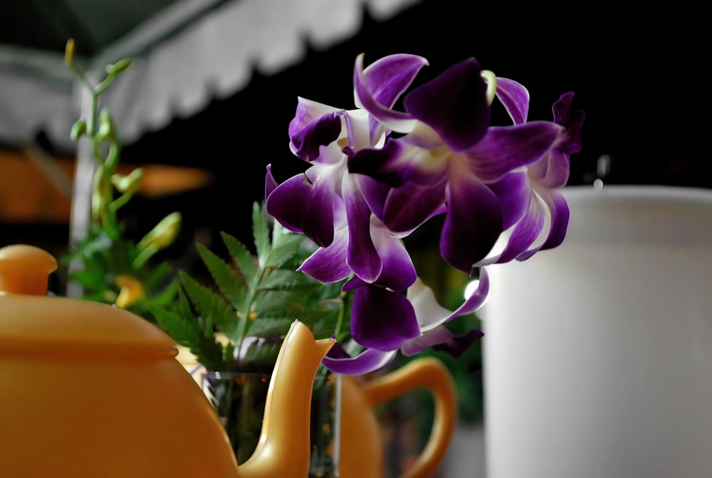 a teapot with a flower in it next to a cup