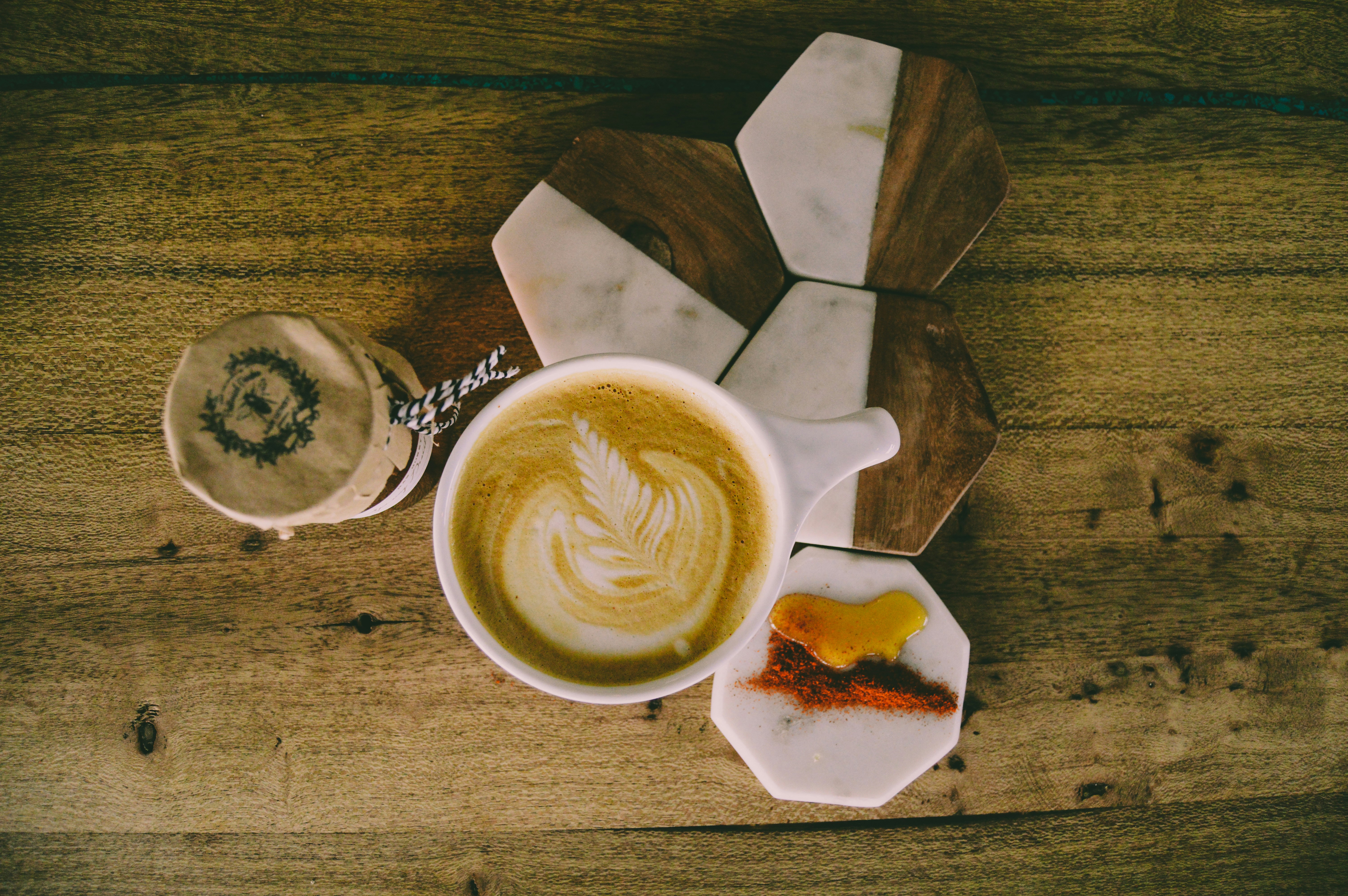 Latte on a wooden table beside a small dessert