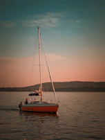A couple enjoying a serene sunset cruise aboard a classic sailboat with polished wood finishes.