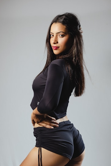 Elegant Taichung model posing confidently in a sleek black outfit with soft pink lighting background