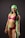 A woman is wearing a vibrant swimsuit consisting of pink, black, and green colors. She has a bright smile and is accessorized with a matching green headscarf. Her posture is confident, and she has visible tattoos on her arms and stomach.