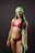A woman is wearing a vibrant swimsuit consisting of pink, black, and green colors. She has a bright smile and is accessorized with a matching green headscarf. Her posture is confident, and she has visible tattoos on her arms and stomach.