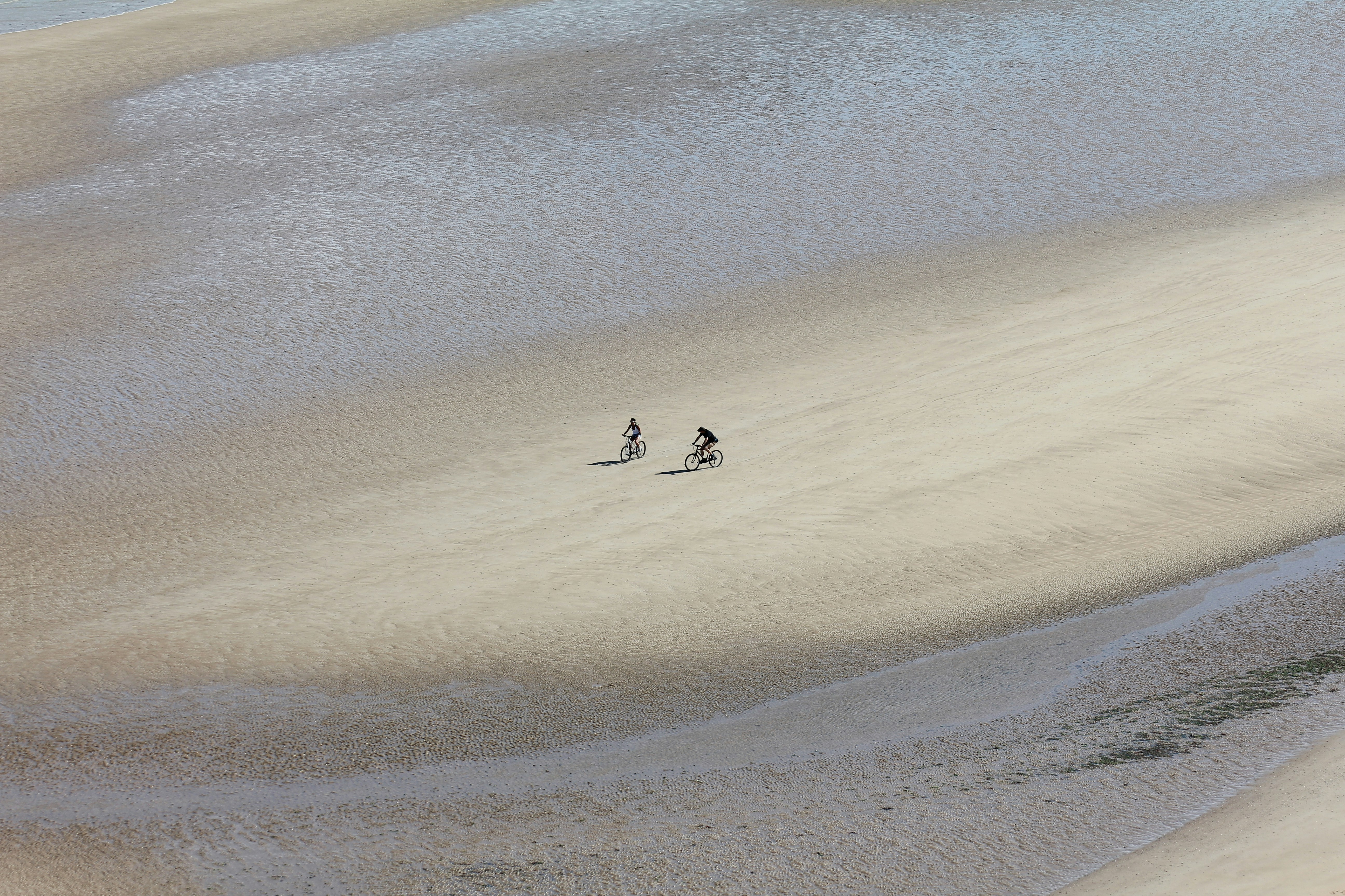 a couple of people riding skis across a sandy beach