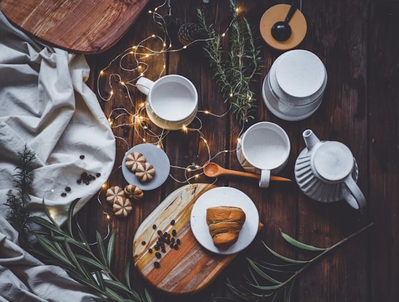 A cozy scene showing a variety of colorful cups arranged on a wooden table with natural light streaming in.