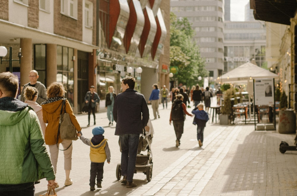 a group of people walking down a street next to tall buildings