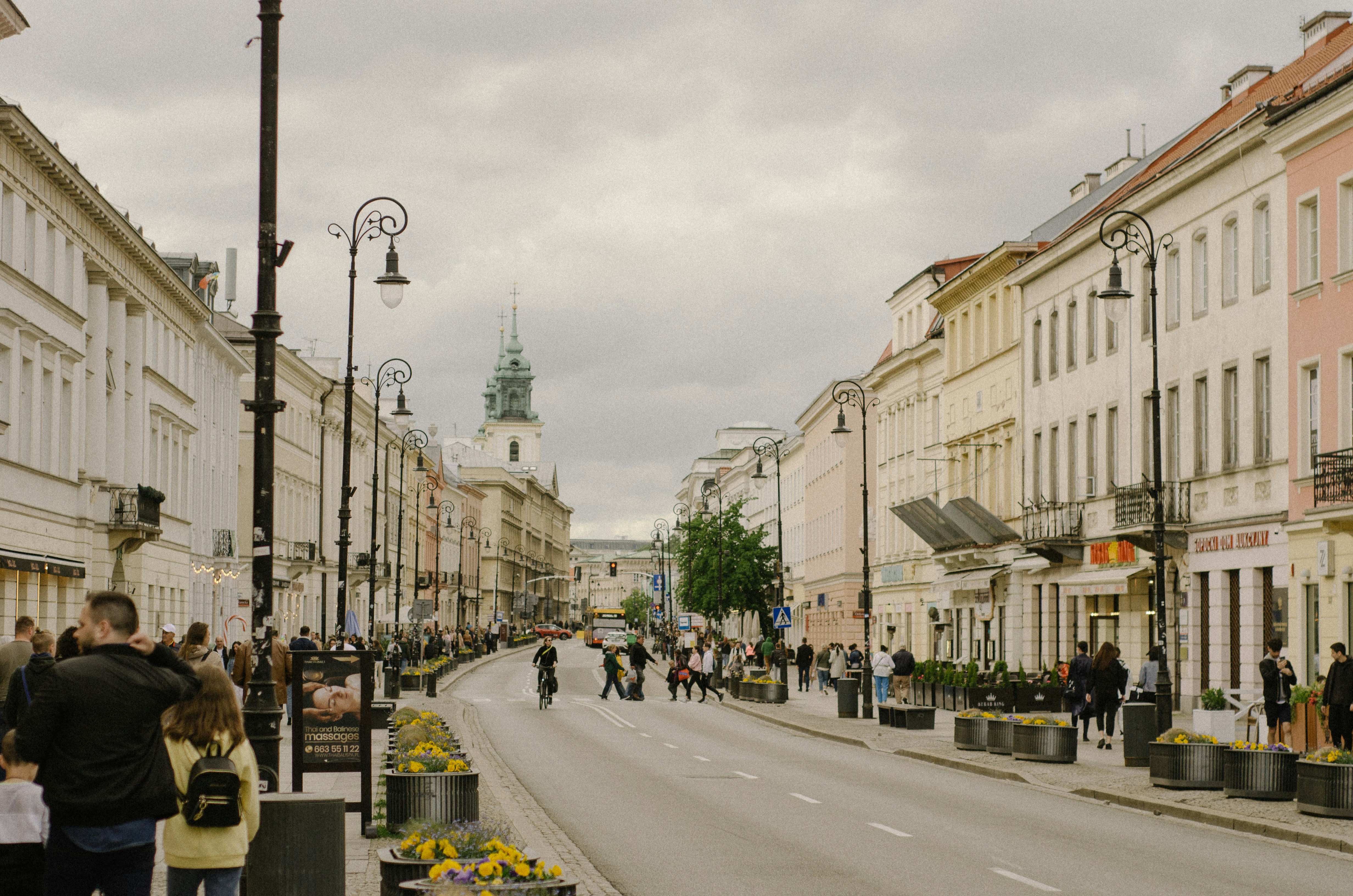 a group of people walking down a street next to tall buildings, 