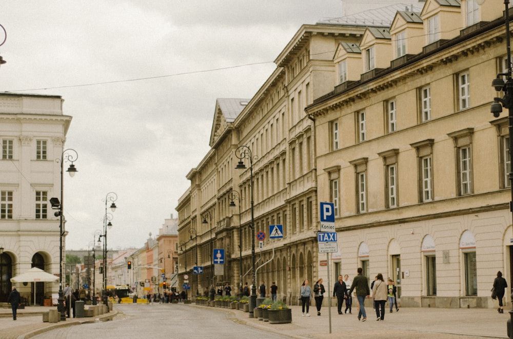 a group of people walking down a street next to tall buildings