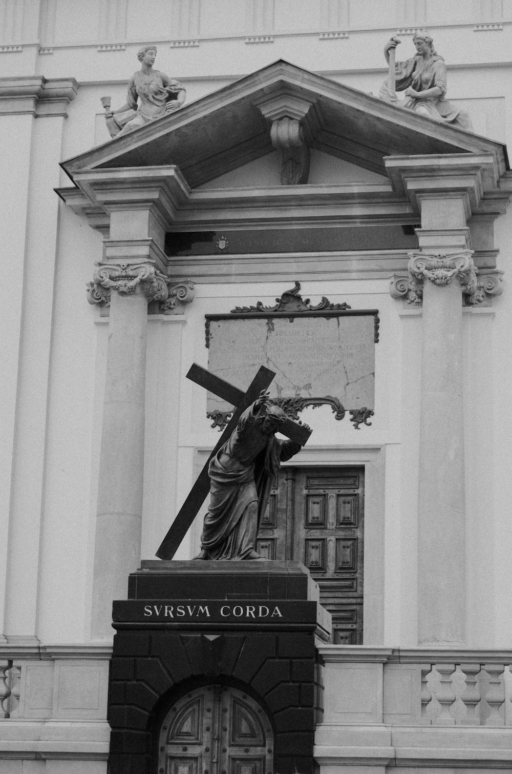 a black and white photo of a statue of jesus carrying the cross