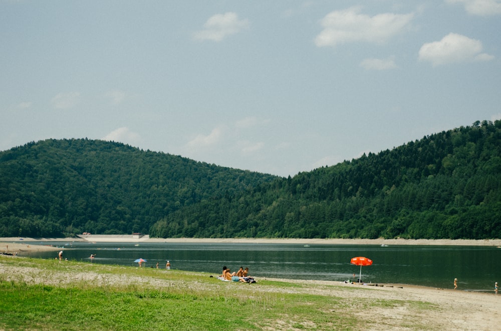 a group of people sitting on a beach next to a body of water