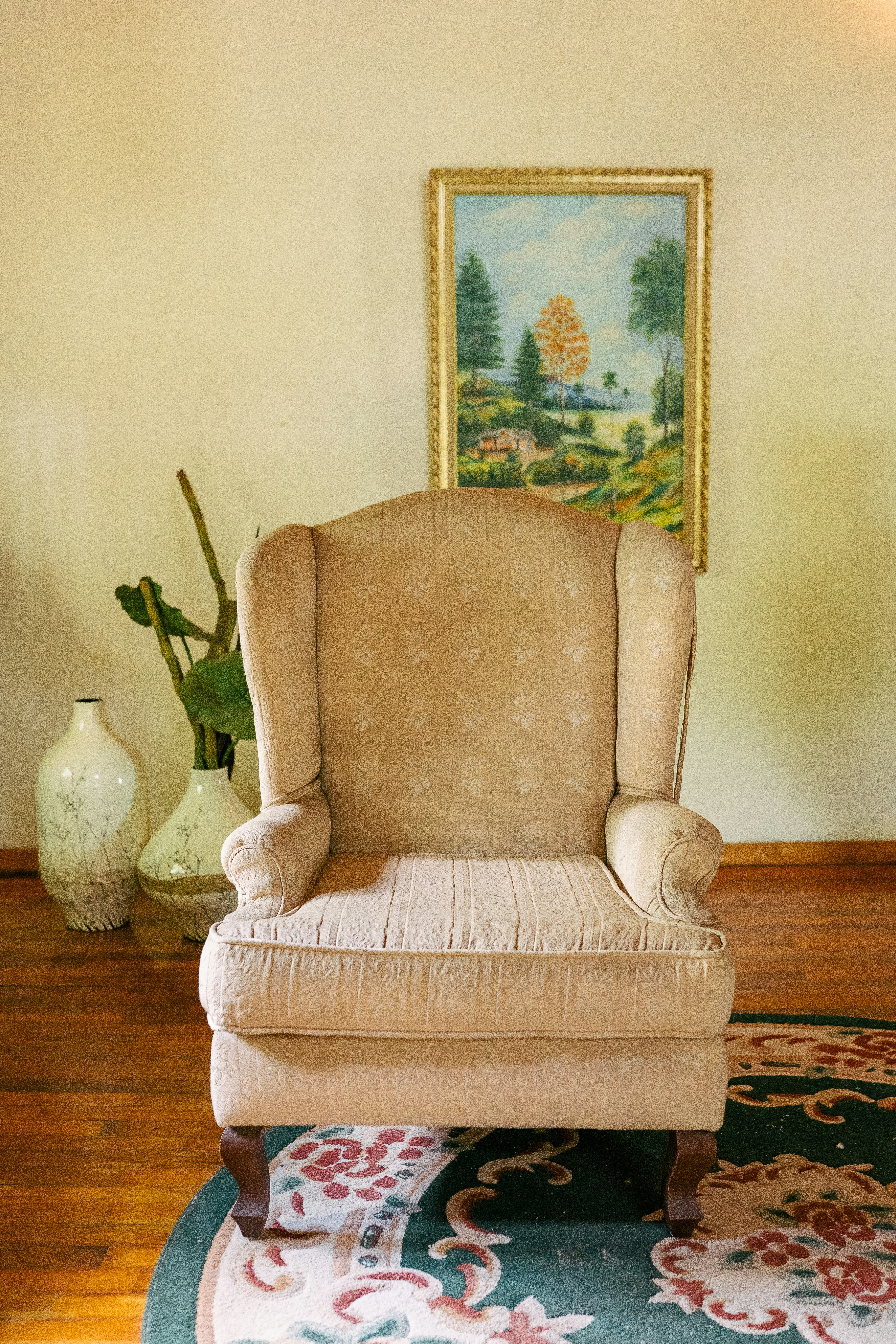 Una silla sentada en una sala de estar junto a una pintura