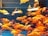 A crowded aquarium filled with numerous small, vibrant goldfish swimming in clear water. The fish display a range of orange and white colors, with some showing intricate patterns. The tank has a blue background that enhances the vivid hues of the fish.