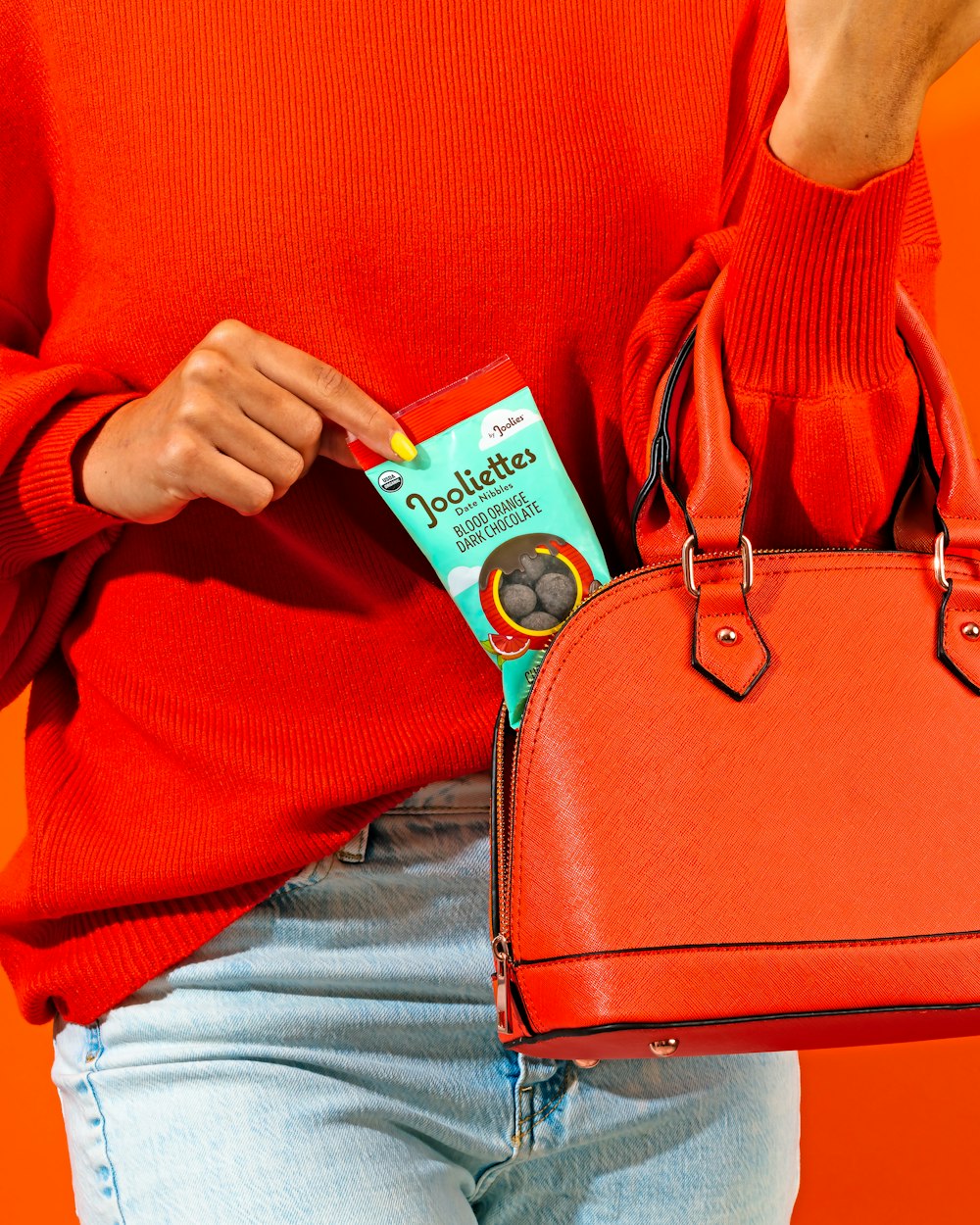 a woman in a red sweater holding a red purse