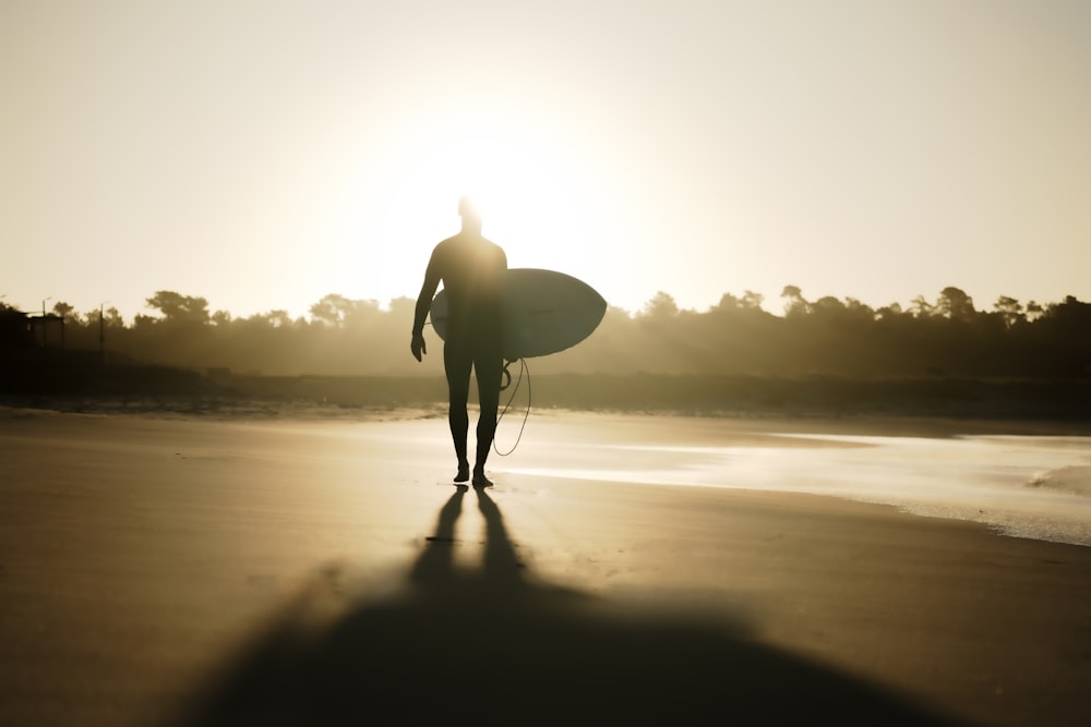 a person walking on a beach with a surfboard