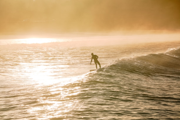 Surfer catching a perfect wave at sunrise on a remote beach