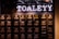 A wall with multiple electrical panels is displayed. Above the panels, a neon sign reads 'TOALETY', which suggests a public restroom indicator. The setup is industrial with a utilitarian aesthetic, featuring dark tones and exposed wiring.