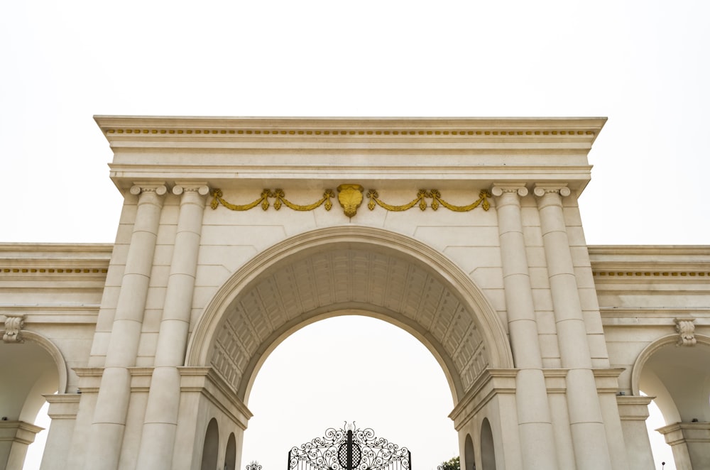 a large white arch with a clock on top of it