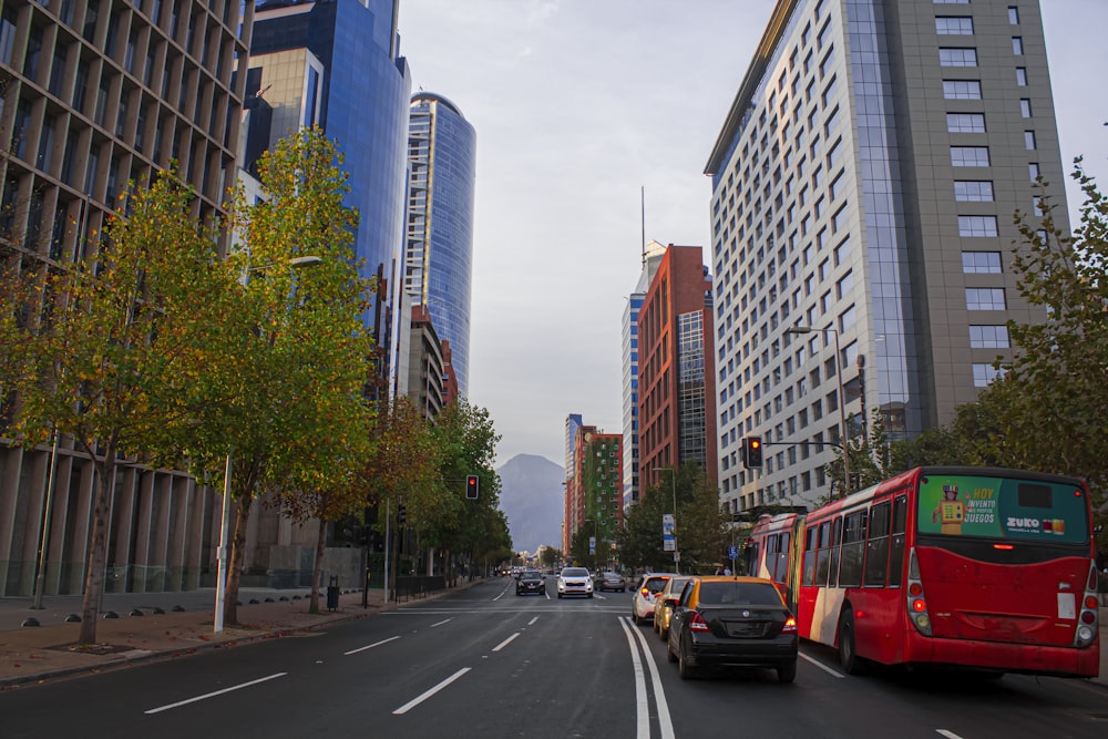 a red bus driving down a street next to tall buildings