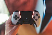 Wireless joystick held by a gamer with colorful LED lights in the background.