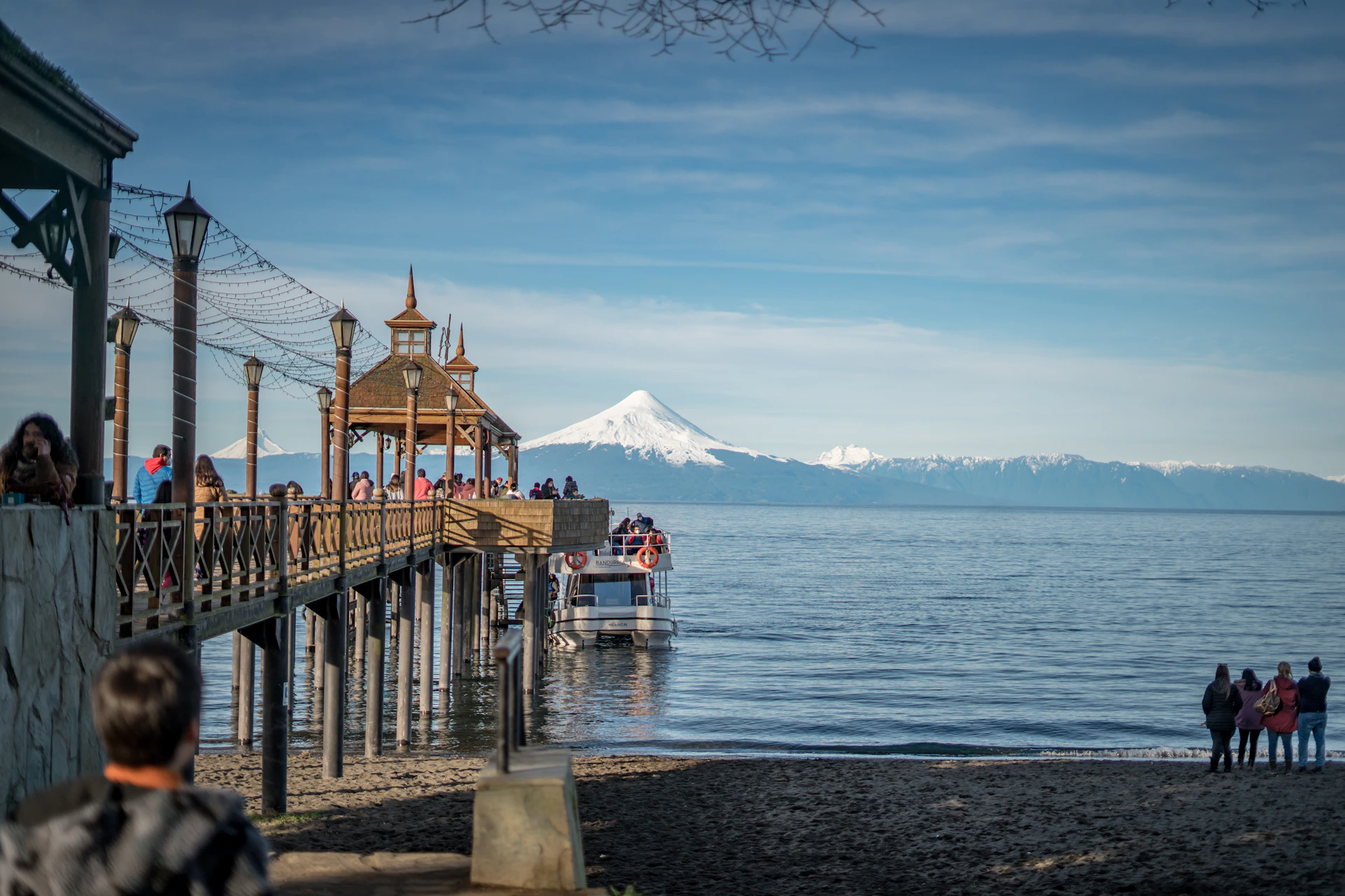a group of people standing on a pier next to a body of water