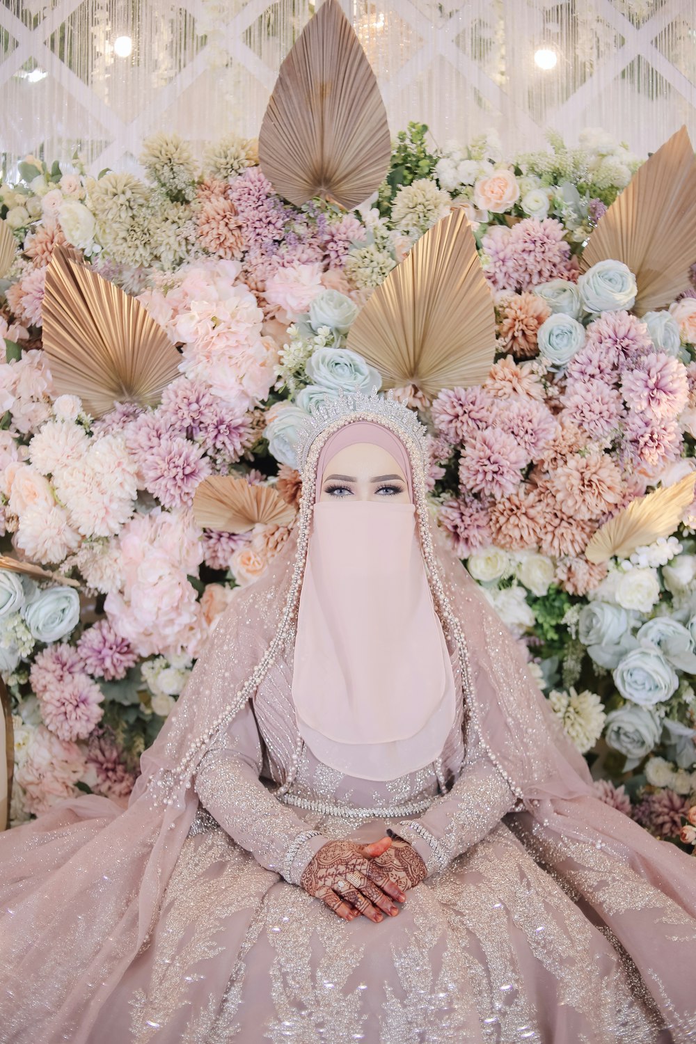 a woman in a wedding dress sitting in front of flowers