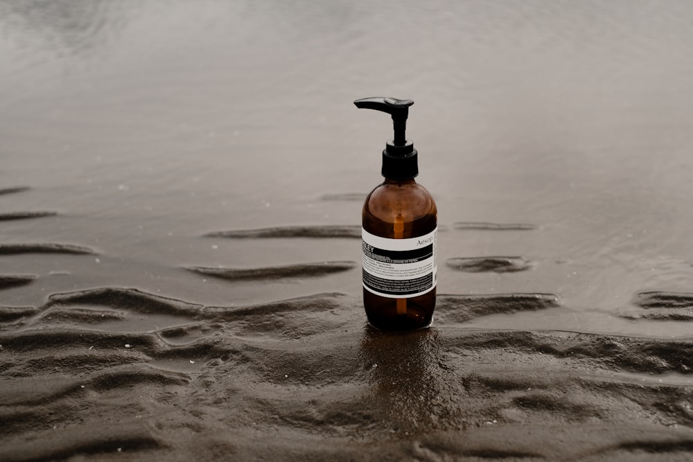 a bottle of soap sitting on top of a wet beach