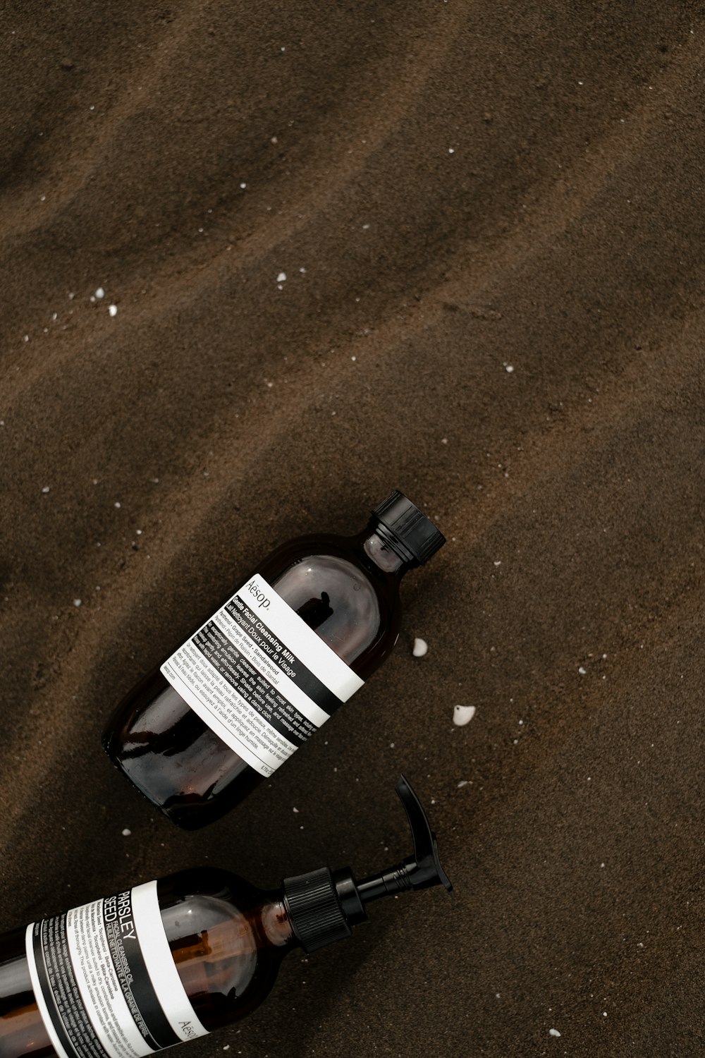a bottle of beer sitting on top of a sandy beach