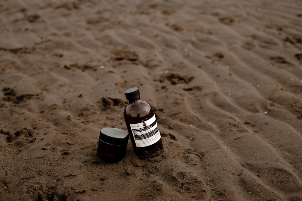 a bottle of lotion sitting on top of a sandy beach