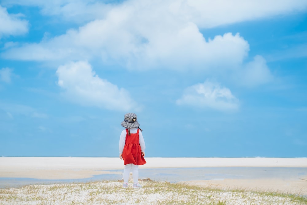 a woman in a red dress standing on a beach