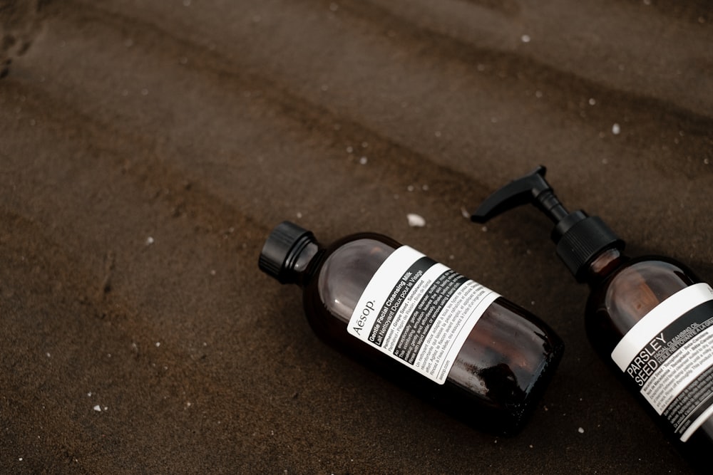 two bottles of lotion sitting on the ground