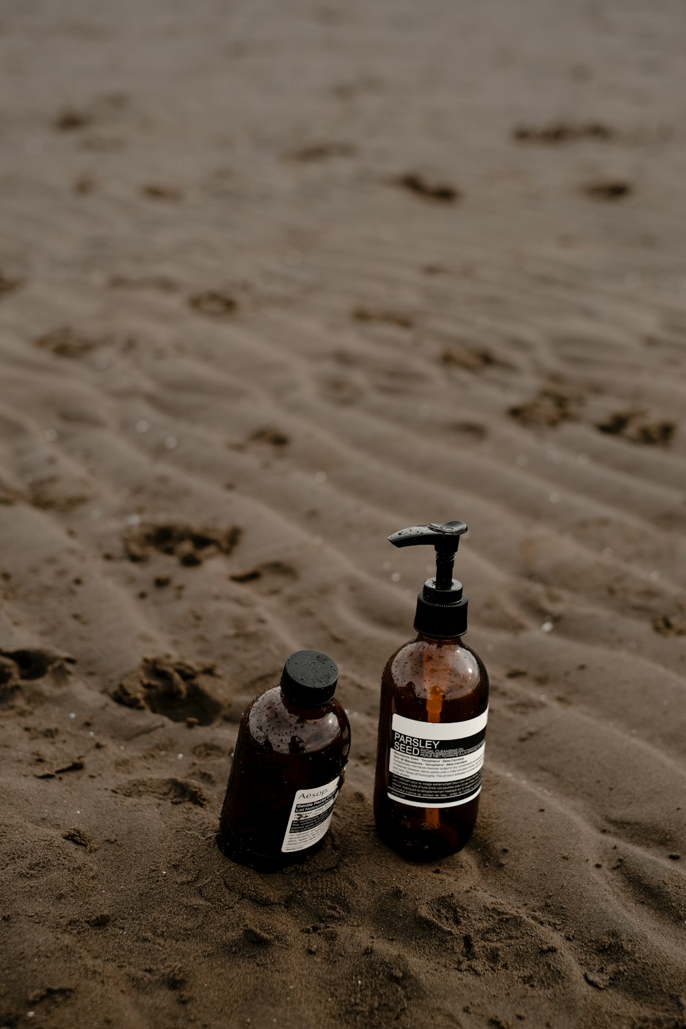 a bottle of lotion sitting on top of a sandy beach