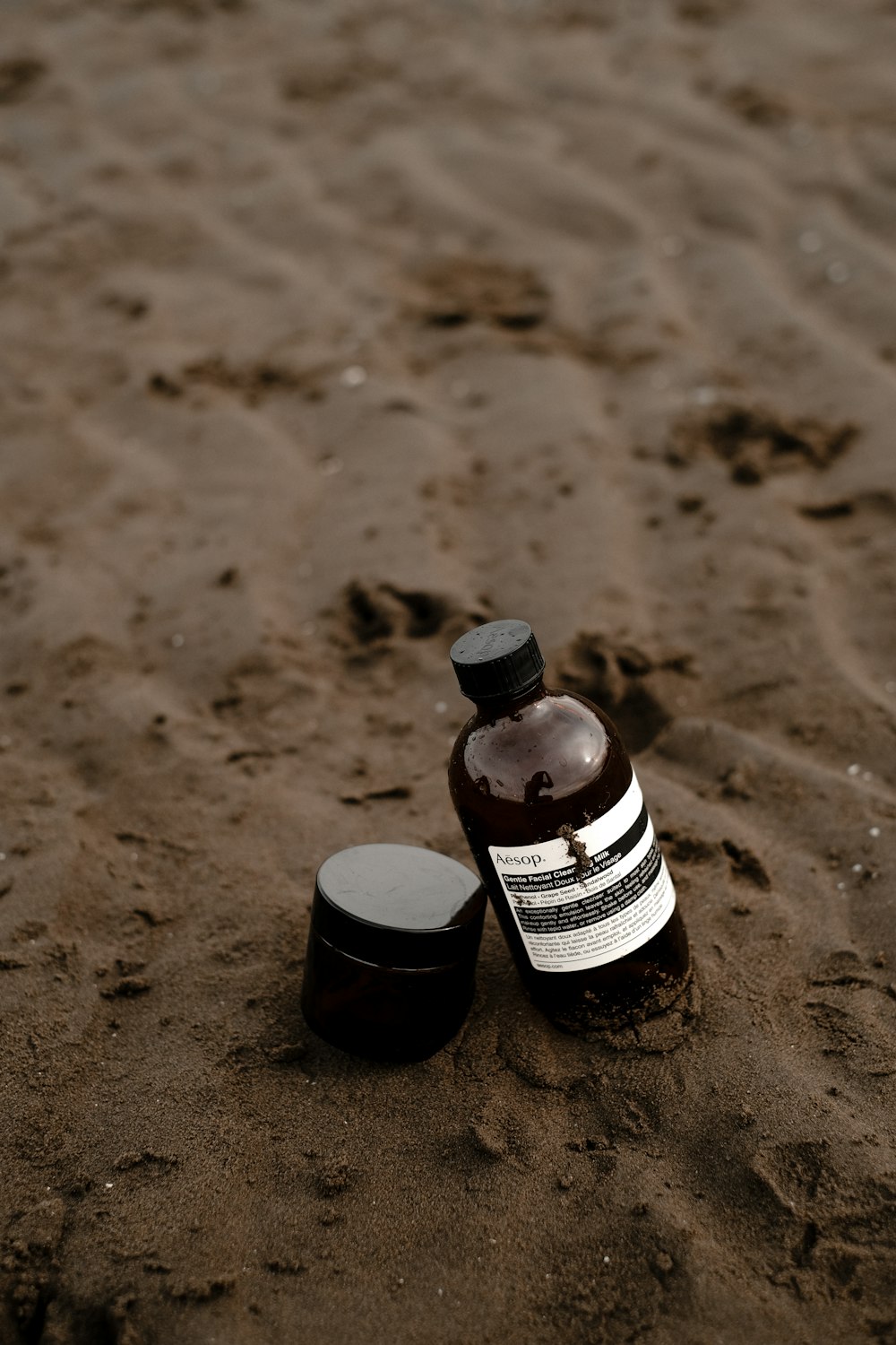 a bottle of lotion sitting in the sand