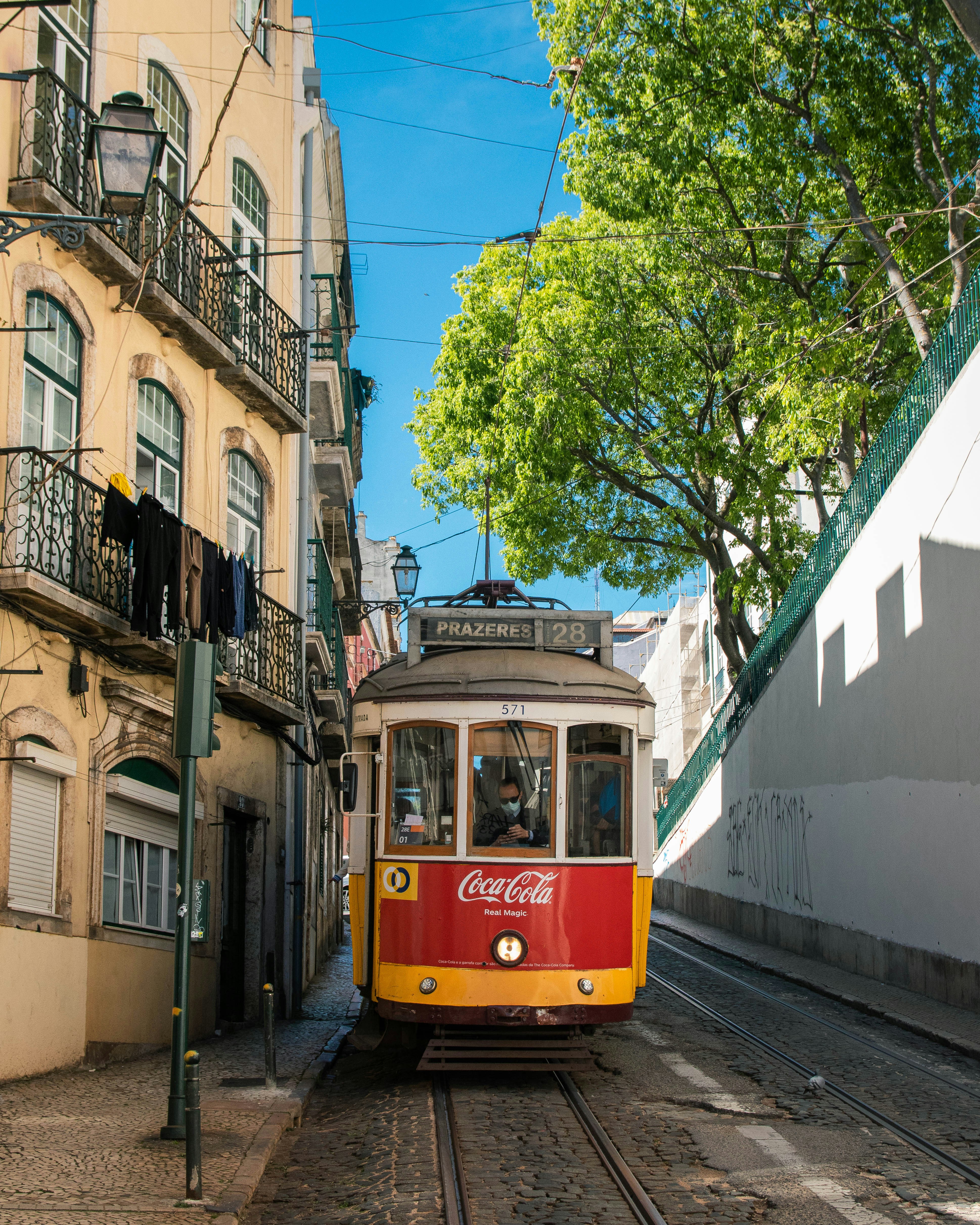 Ein rot-gelber Straßenbahnwagen fährt eine Straße entlang