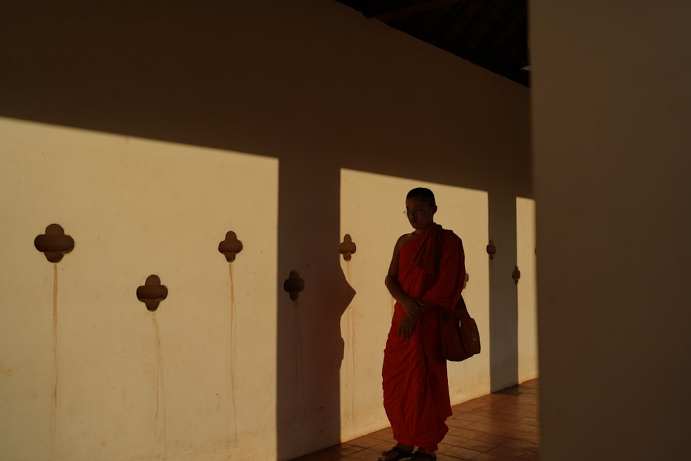 a man in a red robe standing in front of a wall