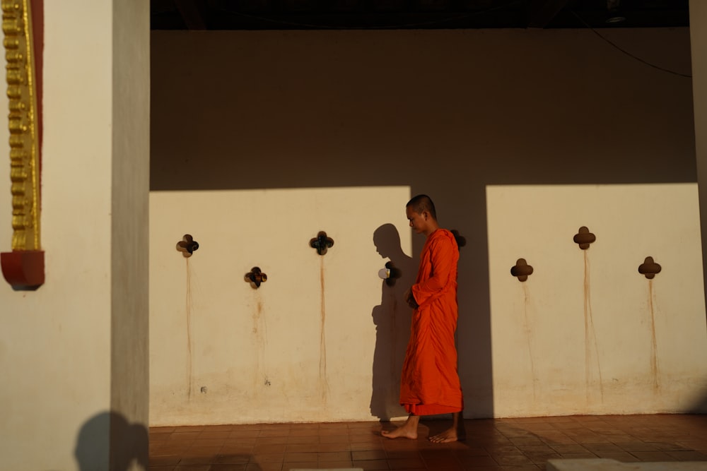 a man in an orange robe standing in front of a wall