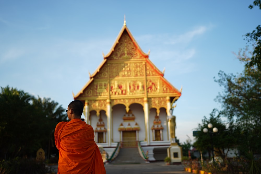 a person in an orange robe standing in front of a building