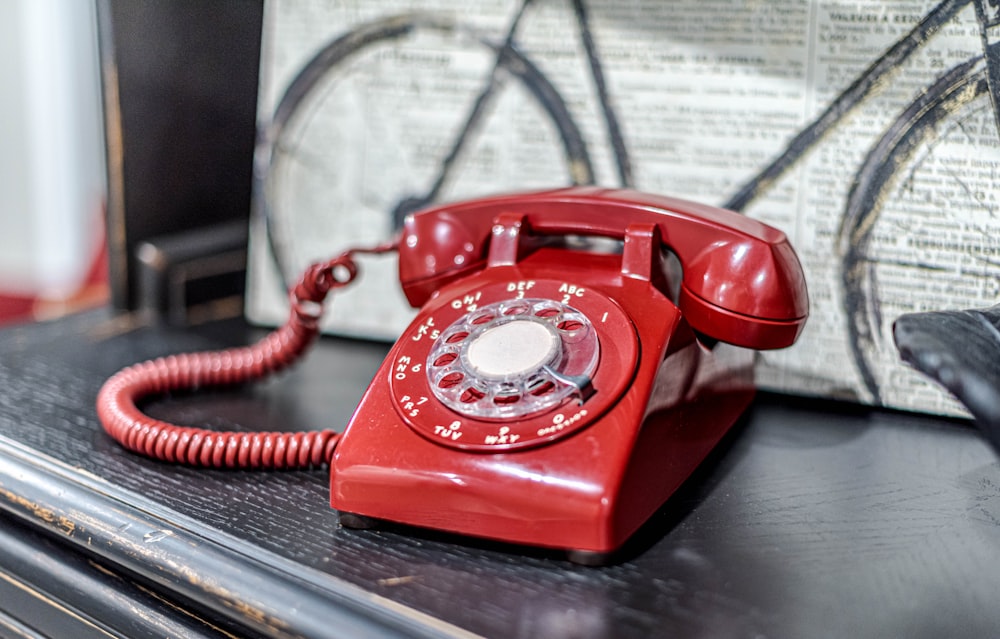 Un teléfono rojo sentado encima de una mesa