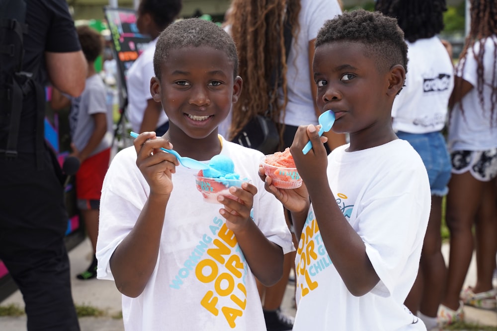 two young boys brushing their teeth in front of a crowd