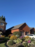 A sturdy wooden garage door freshly installed on a suburban home with blooming flowers nearby.