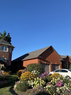 A friendly technician repairing a garage door in a suburban driveway on a sunny day.