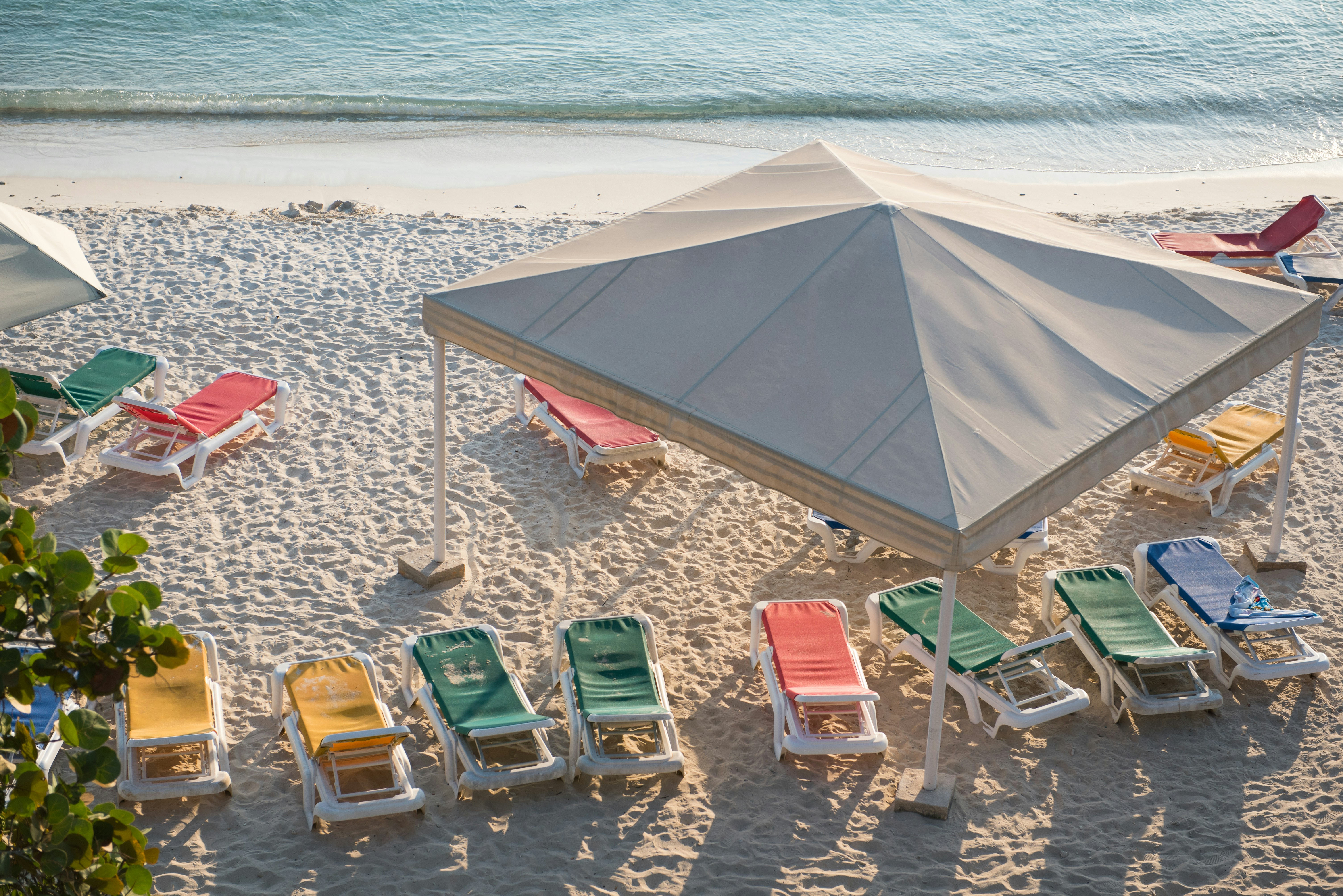 a group of lawn chairs sitting on top of a sandy beach