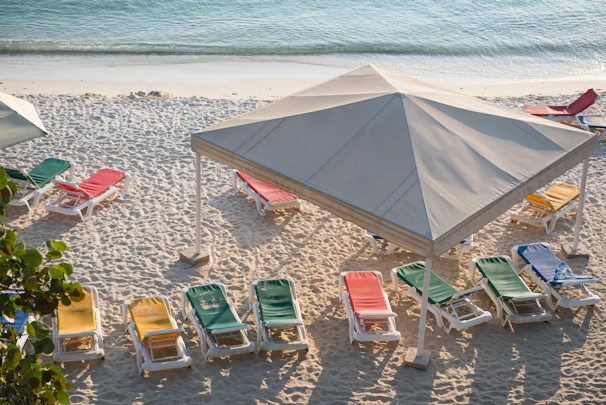 a group of lawn chairs sitting on top of a sandy beach