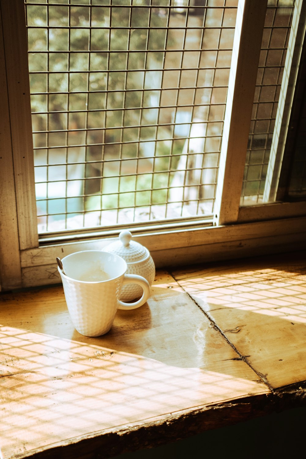 a coffee cup sitting on a table in front of a window