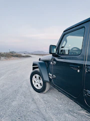Robust black heavy-duty truck parked on a gravel road with mountains in the background.
